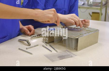 Zwei Frauen werden an ihrem Arbeitsplatz als unrekonalisierbar angesehen. Es handelt sich um medizinische Hygienekleidung. Sie führen Hygiene- und Sterilisationsaufgaben durch Stockfoto