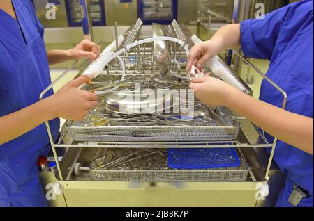 Zwei Frauen werden an ihrem Arbeitsplatz als unrekonalisierbar angesehen. Es handelt sich um medizinische Hygienekleidung. Sie führen Hygiene- und Sterilisationsaufgaben durch Stockfoto