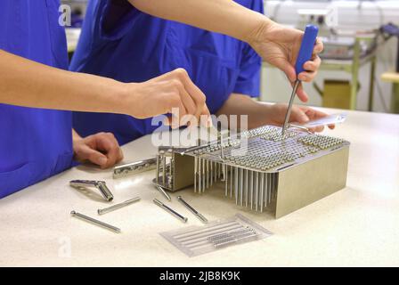 Zwei Frauen werden an ihrem Arbeitsplatz als unrekonalisierbar angesehen. Es handelt sich um medizinische Hygienekleidung. Sie führen Hygiene- und Sterilisationsaufgaben durch Stockfoto