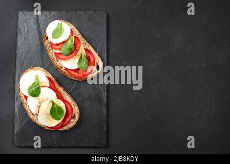 Italienisches Sandwich mit Basilikum-macarella und Tomaten auf dunklem Hintergrund auf Schiefer. Draufsicht mit Platz für Ihren Text. Stockfoto