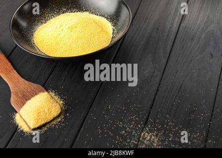 Mais schälte Polenta in dunkler Schale auf dunklem Hintergrund Stockfoto