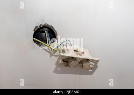 Installation von neuen elektrischen Leitungen, Kunststoffsteckdosen und Elektrodrähten für zukünftige Steckdosen an einer verputzten Wand. DIY Haus Renovierung Konzept. Stockfoto