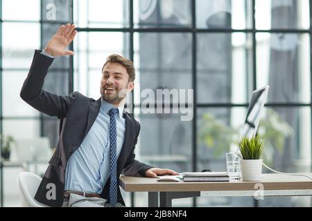 Hallo von Mann im Büro, Indoor winkende Hand Stockfoto