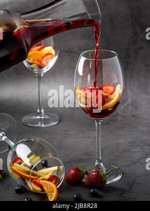 Glas rote Sangria und Früchte auf dunklem Steintisch Stockfoto