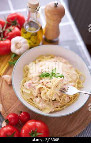 Hausgemachte Pasta Carbonara mit frischem Basilikum und Parmesan in Keramikschale Stockfoto