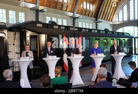 03. Juni 2022, Brandenburg, Potsdam: Dietmar Woidke (M, SPD), Ministerpräsident von Brandenburg, spricht im Rahmen einer Pressekonferenz nach dem "Berlin-Brandenburg Rail Summit" zusammen mit Lisa, Frerichs, Regierungssprecherin im Senatskanzlei (l-r), Jens Bergmann, Mitglied des Vorstands für Infrastrukturplanung DB-Netz AG, Franziska Giffey (SPD), Regierende Bürgermeisterin von Berlin, Und Alexander Kaczmarek, Konzernbeauftragter der Deutschen Bahn für die Region. Im Hintergrund ist ein restaurierter preußischer Schnellzug aus dem Jahr 1912 zu sehen. Es wurden Gespräche über die weitere Entwicklung der Schieneninfrastruktur geführt Stockfoto