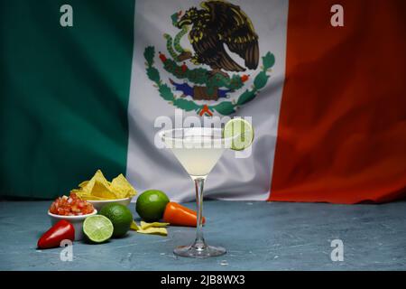 Ein Glas leckeren margarita-Cocktail, Nachos und Salsa-Sauce auf dem Tisch gegen die Flagge Mexikos Stockfoto