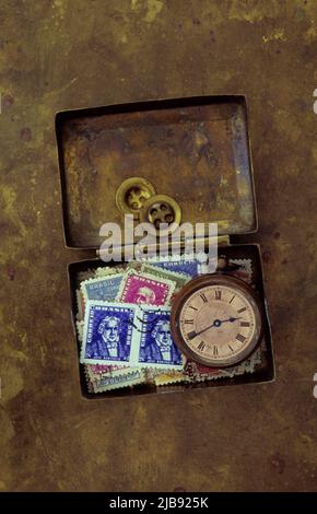 Antike Messingbox mit Vintage Taschenuhr, zwei Messingknöpfen und alten gebrauchten Briefmarken Brasiliens Stockfoto