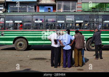 Sultan Bathery, Indien - Januar 2017: Eine Menge älterer Hindu-Männer steht in der Nähe eines alten grünen Personenbusses. Gruppe von indischen Männern im Gespräch. Typischer indischer Bus Stockfoto