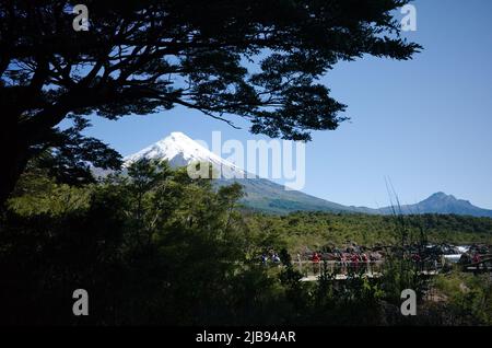 Puerto Varas, Chile - Februar 2020: Blick auf den schneebedeckten Gipfel des Osorno Vulkans durch Baumzweige von der Aussichtsplattform in der Nähe von Saltos de Petrohue Stockfoto