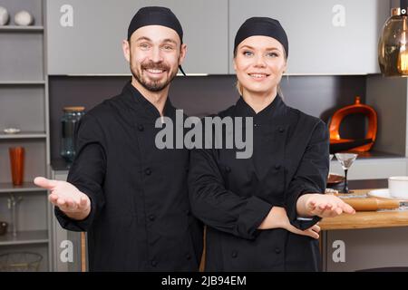 Lächelnde Köche in schwarzer Uniform Stockfoto