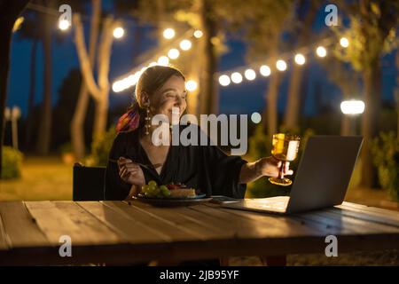 Frau mit Videoanruf und Toasten auf Laptop Stockfoto
