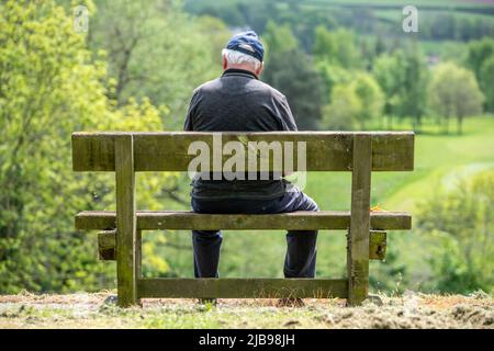 Brecon, 14. 2022. Mai: Ein Mann auf einer Bank mit Blick auf den Fluss Usk in Brecon Stockfoto