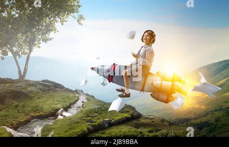 Kind trägt Kopfhörer auf einer Rakete Stockfoto