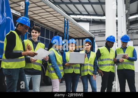 Team von multirassischen Ingenieuren, die in Roboterfabrik arbeiten - Tech Industriekonzept Stockfoto