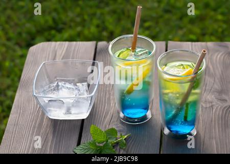 Zwei Gläser mit einem kühlen blauen Lagunencocktail auf einem Holztisch. Selektiver Fokus. Stockfoto