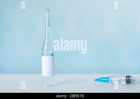 Konzept für Arzneimittel und Arzneimittel mit Spritze und Impfstofffläschchen mit Flüssigkeit. Das Medikamentenfläschchen hat einen leeren Beschriftungsbereich. Herstellung von Impfstoffen und Stockfoto