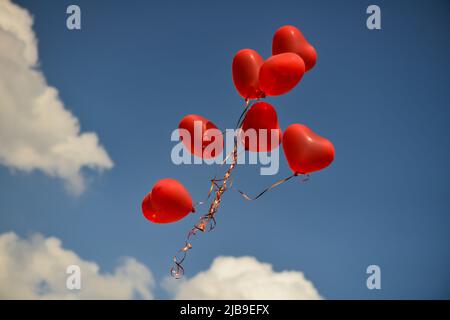 rote, herzförmige Luftballons in den Himmel schweben. Valentinstag-symbol Stockfoto