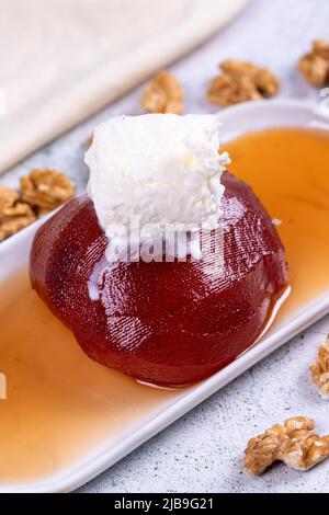 Quitte-Dessert. Traditionelle türkische Küche Delikatessen. Quitte-Dessert mit Creme auf steinernem Hintergrund. Nahaufnahme. Lokaler Name ayva tatlisi Stockfoto