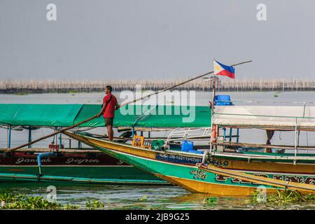 Binangonan, Philippinen. 04.. Juni 2022. Ein Fischer verankert sein Boot im See. Laguna Lake ist der größte See auf den Philippinen und bedeckt eine Fläche von 900 Quadratkilometern oder entspricht 90.000 Hektar. Das Wasser fließt von der Provinz Laguna bis zur Provinz Rizal, dem südlichen Teil von Luzon. Der See bietet Ressourcen wie Transport, Erholung, Lebensunterhalt und vor allem Nahrung für die umliegenden Gemeinden. Laguna Lake wird als Süßwasser der Klasse C klassifiziert, das die Fähigkeit besitzt, Fische und andere aquatische Ressourcen anzubauen. Einige Wasserscheide in der Nähe der Metro Manila Cla Stockfoto