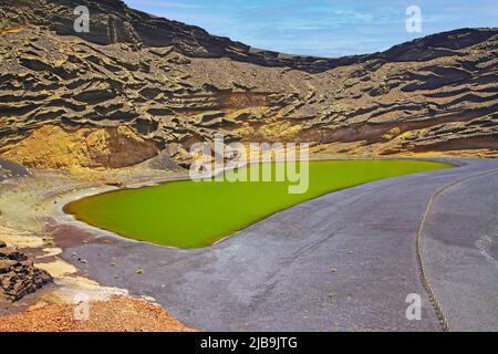 Wunderschönes abgeschiedenes Lagunental, rote Felsen, tiefgrüner See (Lago verde), schwarzer Lavasand, beeindruckende schroffe steile Klippen - El Golfo, Lanzarote Stockfoto