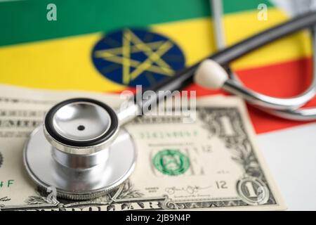 Schwarzes Stethoskop auf äthiopischer Flagge mit US-Dollar-Banknoten, Geschäfts- und Finanzkonzept. Stockfoto