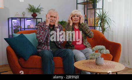 Unzufrieden ältere ältere Familie Großeltern Mann Frau reiben Tempel zu heilen Kopfschmerzen Problem, leiden an Verspannungen und Migräne, Stress, Grimacing bei Schmerzen, Bluthochdruck auf der Couch zu Hause Stockfoto