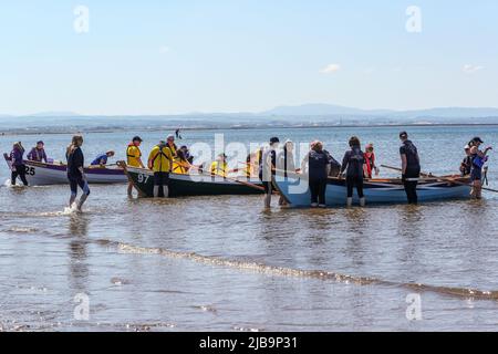 Troon, Großbritannien. 04.. Juni 2022. 04. Juni 2022. Troon, Großbritannien. Der Troon Coastal Rowing Club (TCRC) veranstaltete seine jährliche Regatta auf dem Firth of Clyde, der vom Südstrand Troon, Ayrshire, Großbritannien, aus segelte. Die kleinen Boote sind traditionell, handgefertigt, aus Holz, 4 Crew, Angeln Skiffs, Basierend auf einem 300 Jahre alten Design. Das Rennen erfordert, dass die Teilnehmer eine festgelegte Strecke von nicht weniger als 2 Kilometern zurücklegen, vom Ufer aus und bei der Rückkehr muss ein Teammitglied einen Stock Troon Rock (Süßwaren}) nehmen und mit ihm bis zur Ziellinie laufen. Die Veranstaltung zog Teilnehmer aus verschiedenen Ruderclubs an der Küste Schottlands an Stockfoto