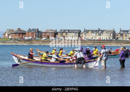 Troon, Großbritannien. 04.. Juni 2022. 04. Juni 2022. Troon, Großbritannien. Der Troon Coastal Rowing Club (TCRC) veranstaltete seine jährliche Regatta auf dem Firth of Clyde, der vom Südstrand Troon, Ayrshire, Großbritannien, aus segelte. Die kleinen Boote sind traditionell, handgefertigt, aus Holz, 4 Crew, Angeln Skiffs, Basierend auf einem 300 Jahre alten Design. Das Rennen erfordert, dass die Teilnehmer eine festgelegte Strecke von nicht weniger als 2 Kilometern zurücklegen, vom Ufer aus und bei der Rückkehr muss ein Teammitglied einen Stock Troon Rock (Süßwaren}) nehmen und mit ihm bis zur Ziellinie laufen. Die Veranstaltung zog Teilnehmer aus verschiedenen Ruderclubs an der Küste Schottlands an Stockfoto