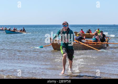 Troon, Großbritannien. 04.. Juni 2022. 04. Juni 2022. Troon, Großbritannien. Der Troon Coastal Rowing Club (TCRC) veranstaltete seine jährliche Regatta auf dem Firth of Clyde, der vom Südstrand Troon, Ayrshire, Großbritannien, aus segelte. Die kleinen Boote sind traditionell, handgefertigt, aus Holz, 4 Crew, Angeln Skiffs, Basierend auf einem 300 Jahre alten Design. Das Rennen erfordert, dass die Teilnehmer eine festgelegte Strecke von nicht weniger als 2 Kilometern zurücklegen, vom Ufer aus und bei der Rückkehr muss ein Teammitglied einen Stock Troon Rock (Süßwaren}) nehmen und mit ihm bis zur Ziellinie laufen. Die Veranstaltung zog Teilnehmer aus verschiedenen Ruderclubs an der Küste Schottlands an Stockfoto