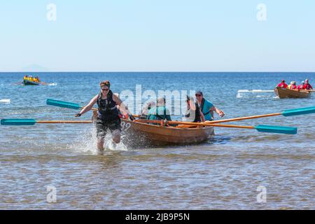 Troon, Großbritannien. 04.. Juni 2022. 04. Juni 2022. Troon, Großbritannien. Der Troon Coastal Rowing Club (TCRC) veranstaltete seine jährliche Regatta auf dem Firth of Clyde, der vom Südstrand Troon, Ayrshire, Großbritannien, aus segelte. Die kleinen Boote sind traditionell, handgefertigt, aus Holz, 4 Crew, Angeln Skiffs, Basierend auf einem 300 Jahre alten Design. Das Rennen erfordert, dass die Teilnehmer eine festgelegte Strecke von nicht weniger als 2 Kilometern zurücklegen, vom Ufer aus und bei der Rückkehr muss ein Teammitglied einen Stock Troon Rock (Süßwaren}) nehmen und mit ihm bis zur Ziellinie laufen. Die Veranstaltung zog Teilnehmer aus verschiedenen Ruderclubs an der Küste Schottlands an Stockfoto