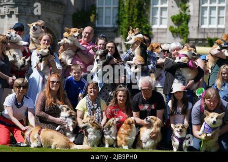 Corgis und ihre Besitzer auf dem Rasen in Balmoral während einer Veranstaltung mit der Corgi Society of Scotland anlässlich des Platin-Jubiläums von Königin Elizabeth II. Das Schloss in Aberdeenshire ist das Ferienhaus aus dem 19.. Jahrhundert, in dem die Königin und Mitglieder der königlichen Familie jedes Jahr zwischen August und September ihren traditionellen Urlaub verbringen. Bilddatum: Samstag, 4. Juni 2022. Stockfoto