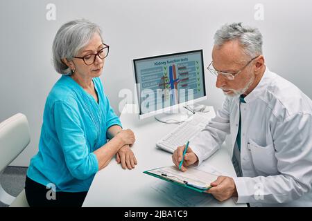 Ältere Frau während einer Konsultation mit einem Urologen über Nierenerkrankungen und Behandlung in der medizinischen Klinik. Gesundheit der Nieren Stockfoto