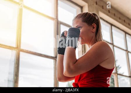 Porträt einer jungen, fitgen Boxerin mit Verband an den Händen in defensiver Position. Sport, aktiver Lebensstil. Speicherplatz kopieren Stockfoto