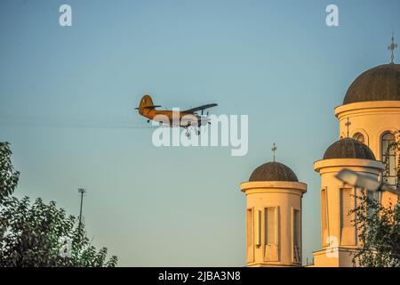 Antonov AN-2 Flugzeug, das an der Kathedrale vorbeifährt Stockfoto