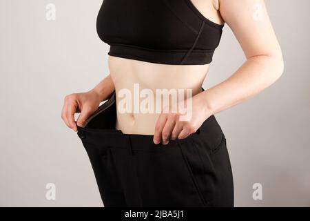 Eine Frau in großen Hosen nach dem Abnehmen, eine schöne weibliche Figur, das Konzept der Ernährung und gesunde Ernährung Stockfoto