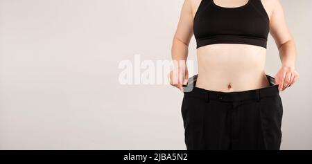 Eine Frau in großen Hosen nach dem Abnehmen, eine schöne weibliche Figur, das Konzept der Ernährung und gesunde Ernährung Stockfoto