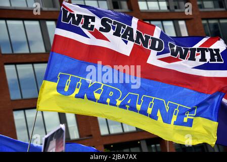 Manchester, Großbritannien, 4.. Juni 2022. Eine Flagge kombiniert die Farben der Union Jack und der ukrainischen Flaggen mit dem Text „Wir stehen mit der Ukraine“. Anti-Kriegs-Kundgebung „steht mit der Ukraine“, ein Protest gegen die russische Invasion der Ukraine in Piccadilly Gardens, im Zentrum von Manchester, England, Großbritannien und den Britischen Inseln. Dies ist der sechzehnte Samstag, an dem der Protest stattgefunden hat. Die Proteste werden vom Ukrainischen Kulturzentrum „Dnipro“ Manchester organisiert. Quelle: Terry Waller/Alamy Live News Stockfoto