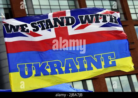 Manchester, Großbritannien, 4.. Juni 2022. Eine Flagge kombiniert die Farben der Union Jack und der ukrainischen Flaggen mit dem Text „Wir stehen mit der Ukraine“. Anti-Kriegs-Kundgebung „steht mit der Ukraine“, ein Protest gegen die russische Invasion der Ukraine in Piccadilly Gardens, im Zentrum von Manchester, England, Großbritannien und den Britischen Inseln. Dies ist der sechzehnte Samstag, an dem der Protest stattgefunden hat. Die Proteste werden vom Ukrainischen Kulturzentrum „Dnipro“ Manchester organisiert. Quelle: Terry Waller/Alamy Live News Stockfoto