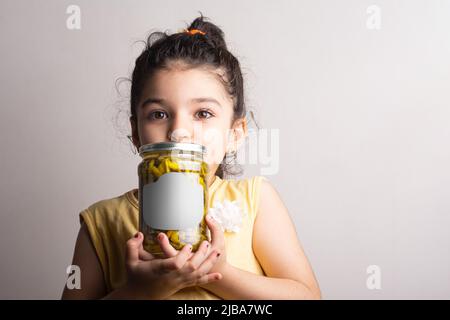 Kleines Mädchen hält einen eingelegten Pfeffer konservieren an den Händen, editierbare Modell-up-Serie Vorlage bereit für Ihr Design, Flasche Label Auswahlpfad enthalten. Stockfoto