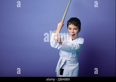 Porträt eines selbstbewussten, starken kaukasischen Jungen Aikido-Wrestlers, der einen traditionellen Samurai-Hakama-Kimono-Lernkampf mit Bambusbokken trägt. Aikido Stockfoto