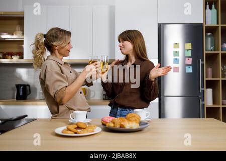 Tochter und Mutter trinken Saft und reden über persönliche Dinge in der Küche Stockfoto