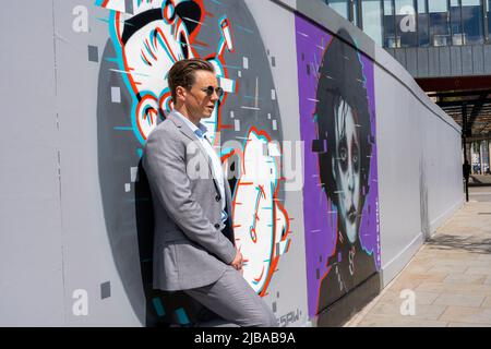 Ipswich Suffolk UK May 27 2022: Ein hübscher Geschäftsmann in einem grauen Anzug vor einigen städtischen Kunstwerken
