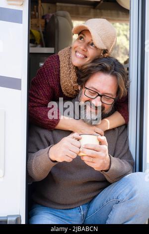 Porträt eines erwachsenen Mannes und einer Frau, die an der Tür eines Wohnwagens sitzen und den Urlaub genießen. Menschen auf der Straße Lifestyle van Leben Stockfoto