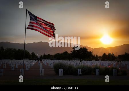 Die amerikanische Flagge schwingt beim Sonnenuntergang auf dem Fort Bliss National Cemetery in El Paso, Texas. Stockfoto