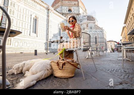 Frau, die mit ihrem Hund auf der Cafeterrasse in der Nähe des berühmten Doms in Florenz sitzt Stockfoto