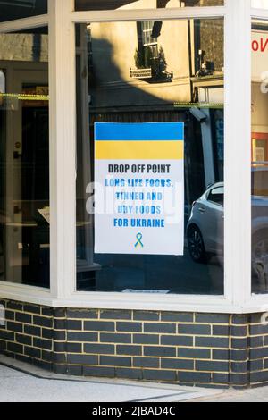 Ein Schild in einem Schaufenster wirbt für einen Abgabeort für Lebensmittel für die Ukraine. Stockfoto