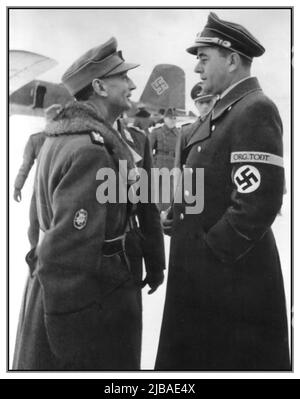 Jahrgang WW2 Nazi-Besuch in Norwegen von Albert Speer (rechts) unusally in Military Uniform mit Hakenkreuz-Armband und General Edward Dietl im Gespräch auf dem Feldflugplatz bei einem Frontbesuch im Norden Norwegens. Junkers-Flugzeuge im Hintergrund mit Swastika-Symbol auf der Heckflosse des Junkers-Flugzeugs Albert Speer, Edward Dietl Zweiten Weltkrieg während der deutschen Besetzung Norwegens von 1940 bis 1945 wollte Hitler eine „arische“ Gesellschaft mit glänzenden Autobahnen und idealen Städten aufbauen. Die Nazis wollten das besetzte Norwegen mit einer bemerkenswerten Baukampagne unter der Leitung von Speer Date Februar 1944 umgestalten Stockfoto