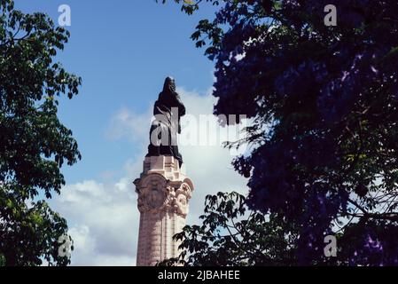 Lissabon, Portugal - 4. Juni 2022: Jacaranda-Baum im Vordergrund mit Marques do Pombal-Statue mit Löwe und Platz in Lissabon, Portugal Stockfoto