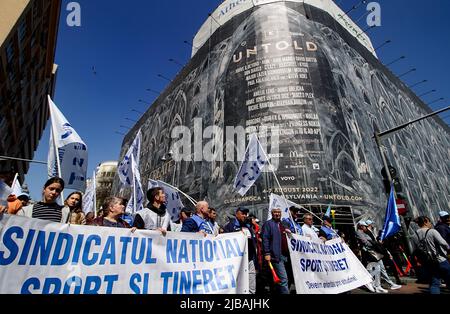 Bukarest, Rumänien - 06. April 2022: Die Demonstranten bei einer Gewerkschaftsversammlung kommen an einer Anzeige für das Untold Festival vorbei, die auf einem sehr großen Banner auf dem Palast des Athene zu sehen ist Stockfoto